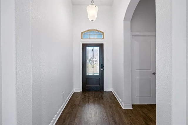 a view of a hallway with wooden floor and a bathroom