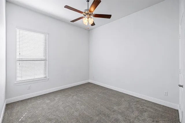 an empty room with a window and a fan
