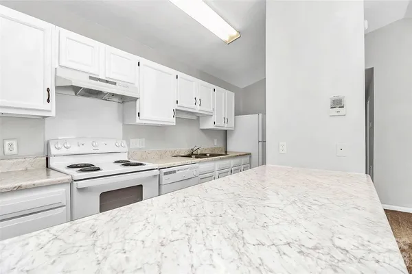 a kitchen with stainless steel appliances granite countertop a stove a sink and white cabinets