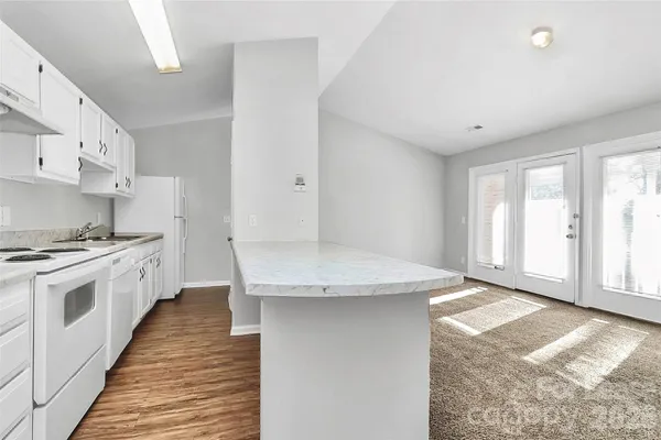 a kitchen with granite countertop white cabinets and white appliances