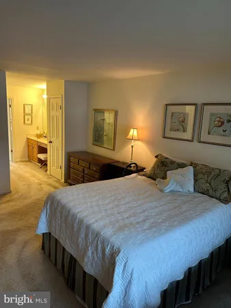 a bedroom with a bed a mirror on dresser and a dining table