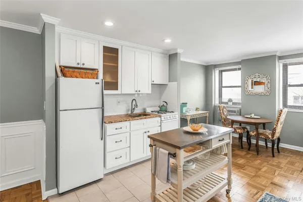 a kitchen with a refrigerator a stove a dining table and chairs with wooden floor