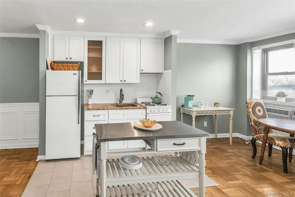 a kitchen with stainless steel appliances granite countertop a stove top oven a refrigerator a dining table and chairs with wooden floor