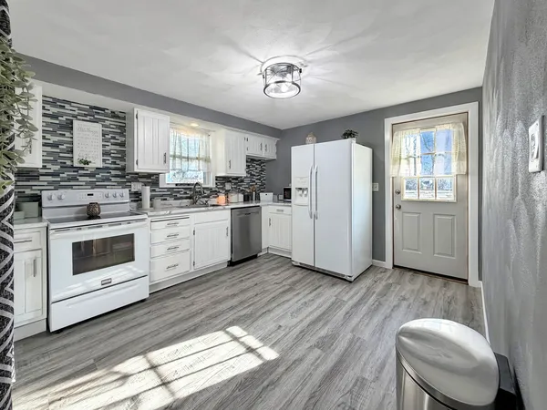 a kitchen with a stove a refrigerator and white cabinets