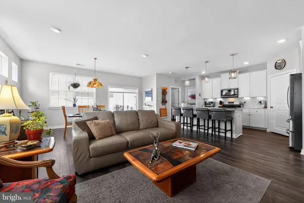 a living room with furniture kitchen view and a wooden floor