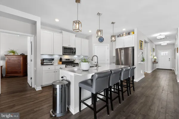a kitchen with stainless steel appliances a dining table chairs stove refrigerator and microwave