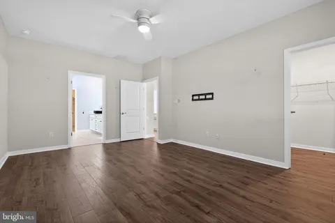 an empty room with wooden floor and ceiling fan