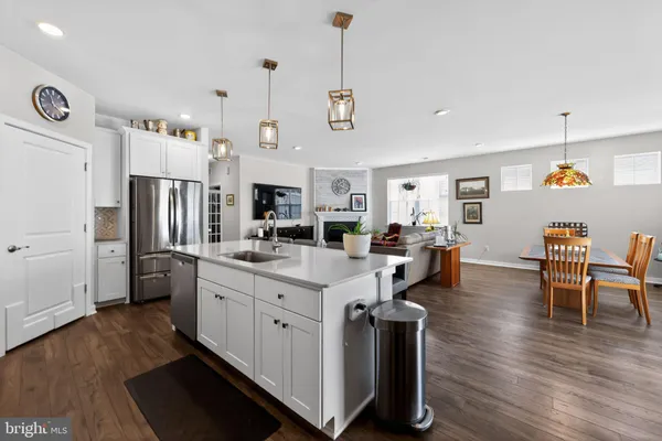 a open kitchen with stainless steel appliances granite countertop a refrigerator a stove oven a dining table and chairs with wooden floor