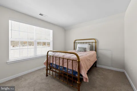 a bedroom with a bed chair and next to a window