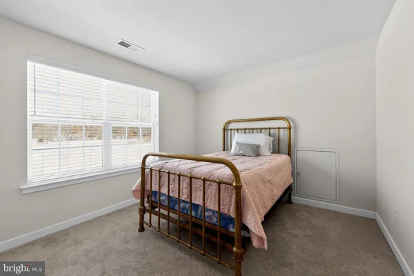 a bedroom with a bed chair and next to a window
