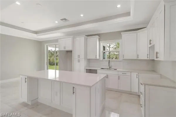 a kitchen with white cabinets and sink