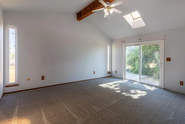 an empty room with windows and ceiling fan