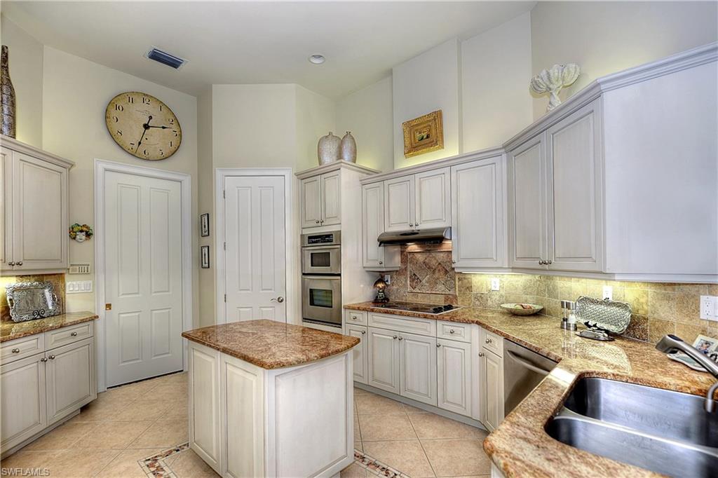 3274 Sedge Place Naples, FL 34105 - Photo 7 of 24 a kitchen with granite countertop a sink a stove top oven and clock
