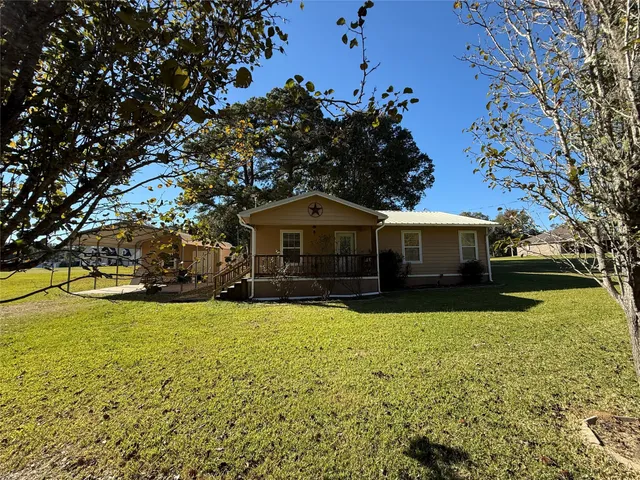 a front view of house with yard and trees in the background