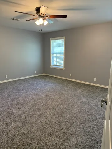 an empty room with windows and fan