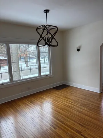 a view of a room with wooden floor chandelier and windows