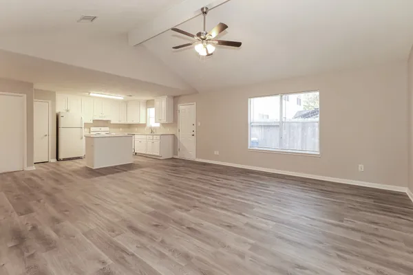 a view of an empty room with a kitchen and a window