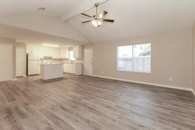 a view of an empty room with a kitchen and a window