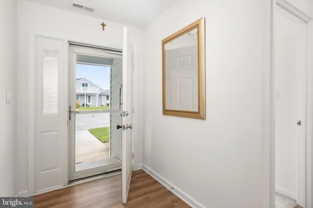 a view of a hallway with wooden floor and a bathroom