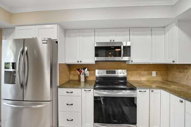 a kitchen with refrigerator a microwave a sink and cabinets