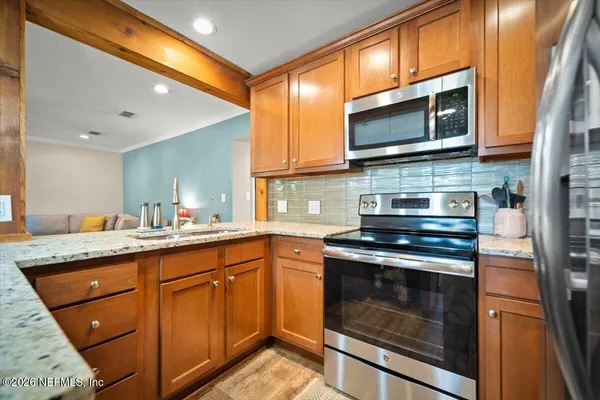 a kitchen with stainless steel appliances granite countertop wooden cabinets stove top oven and sink