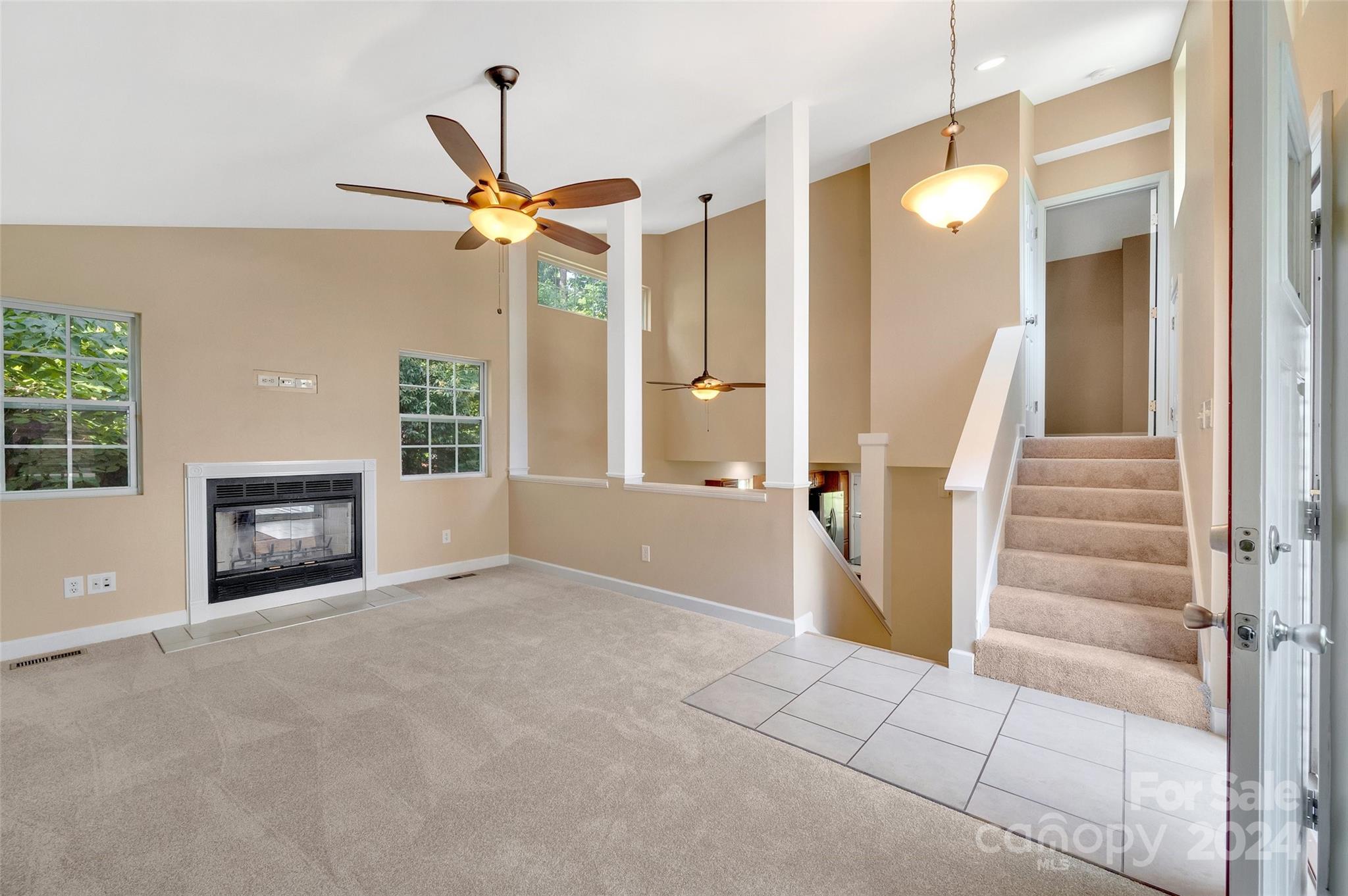 3076 Point Clear Drive Tega Cay, SC 29708 - Photo 4 of 28 wooden floor in an empty room with a fireplace and a chandelier fan