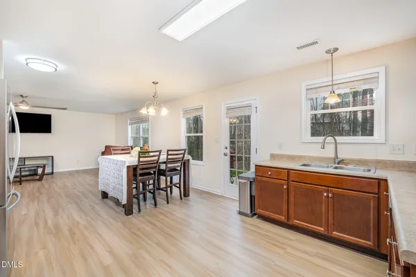 a open kitchen with stainless steel appliances granite countertop a stove a sink dishwasher a dining table and chairs with wooden floor