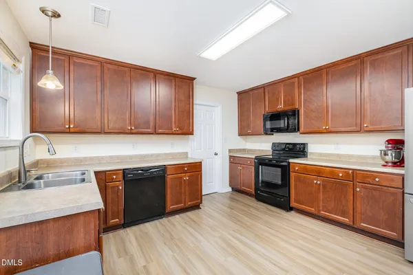 a kitchen with stainless steel appliances granite countertop wooden cabinets a stove top oven a sink and dishwasher with wooden floor