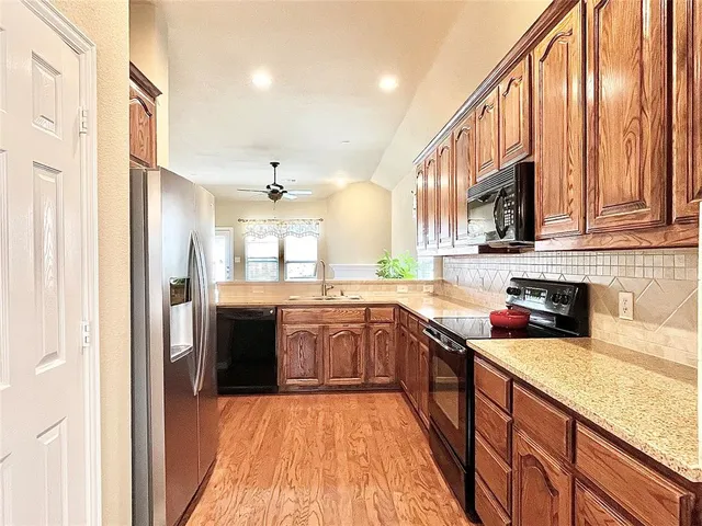 a large kitchen with stainless steel appliances granite countertop a sink and cabinets