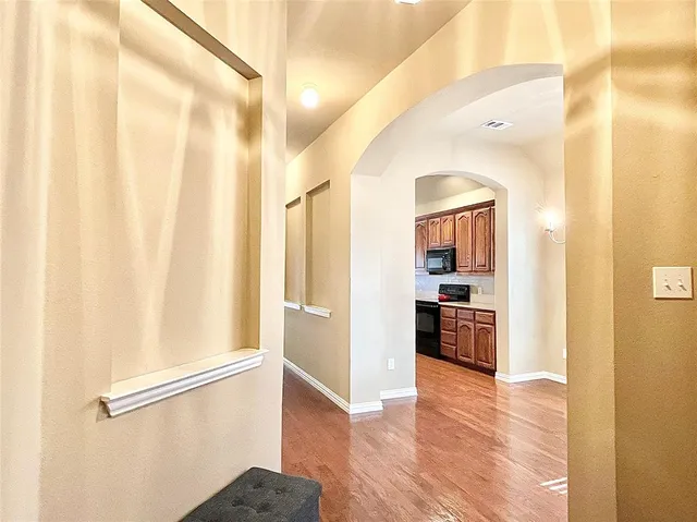 a view of a hallway with wooden floor and a bathroom