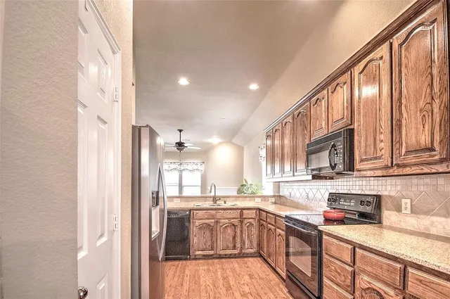 a kitchen with stainless steel appliances granite countertop a refrigerator a sink dishwasher a stove and white countertops with cabinets