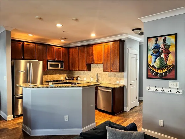 a kitchen with stainless steel appliances granite countertop wooden cabinets a stove top oven a sink and dishwasher