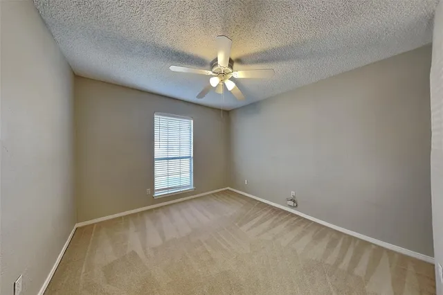 an empty room with windows and ceiling fan