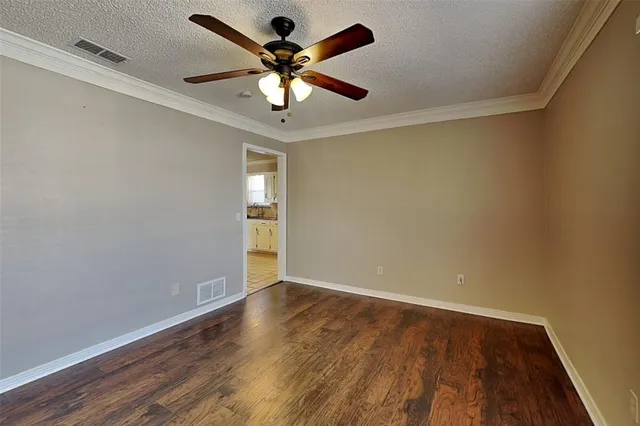 an empty room with wooden floor and ceiling fan