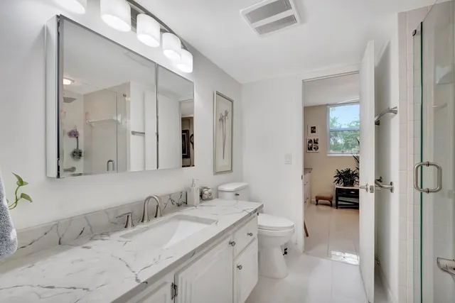 a bathroom with a granite countertop sink mirror and a toilet