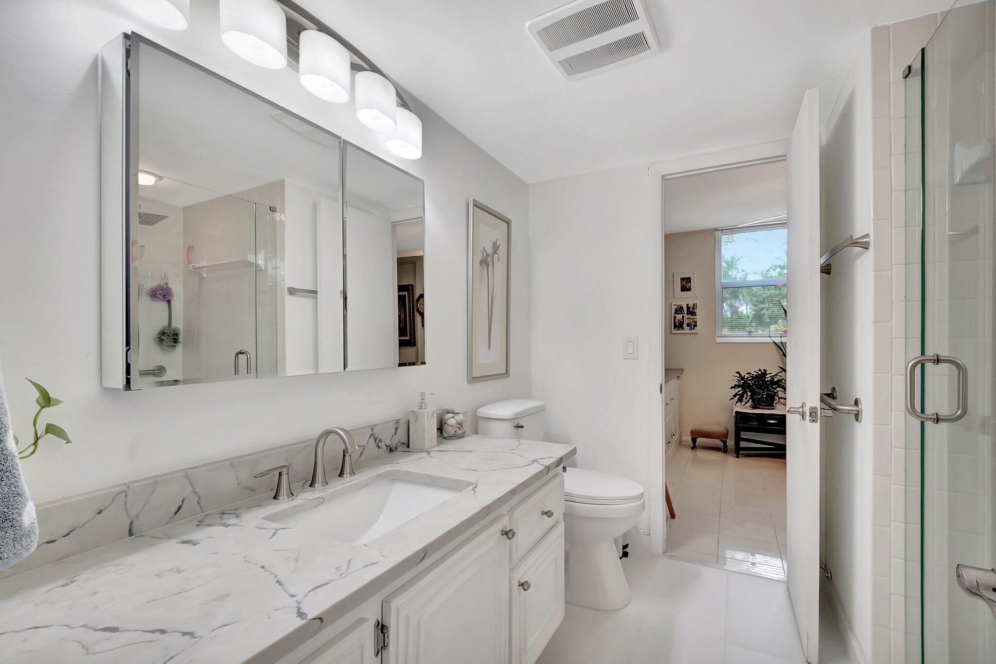 6461 Northwest 2nd Avenue, Unit 1160 Boca Raton, FL 33487 - Photo 17 of 26 a bathroom with a granite countertop sink mirror and a toilet