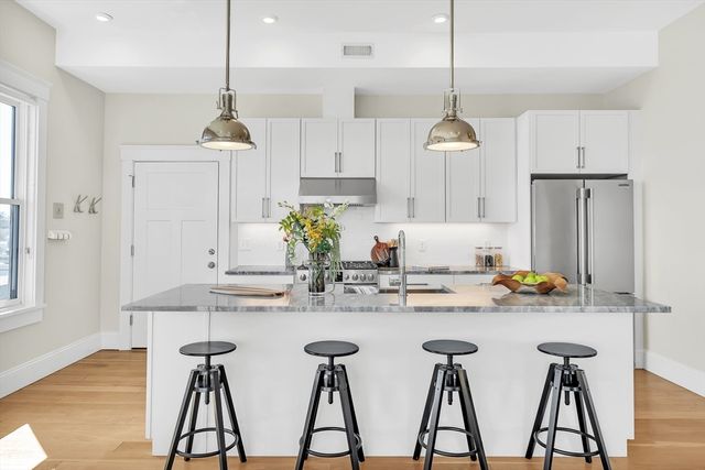 a kitchen with stainless steel appliances kitchen island granite countertop a dining table chairs and white cabinets