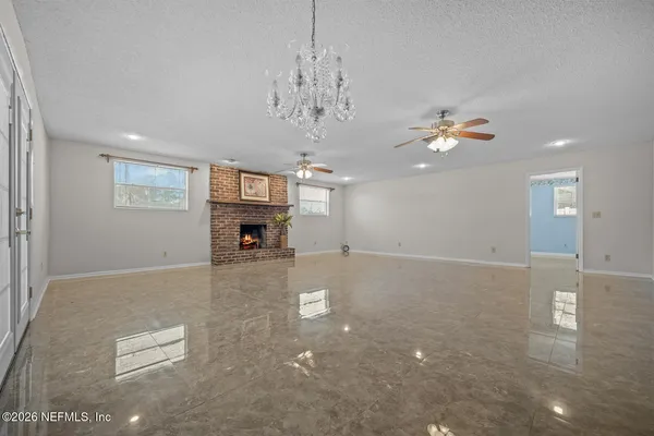 an empty room with a chandelier fan and windows