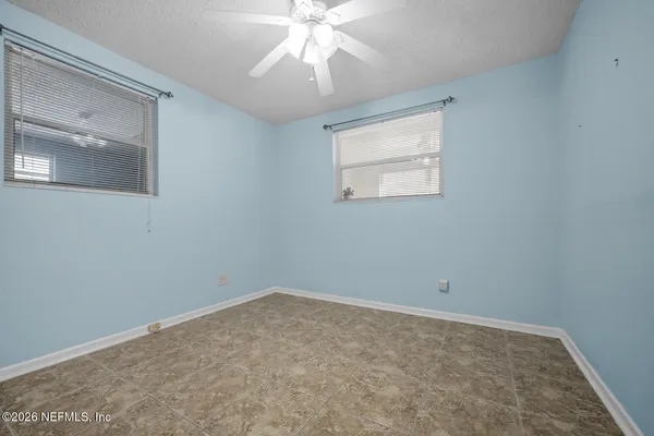 an empty room with a chandelier fan and windows