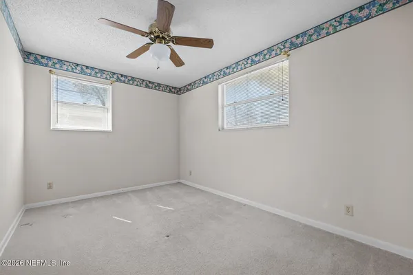 an empty room with windows and fan