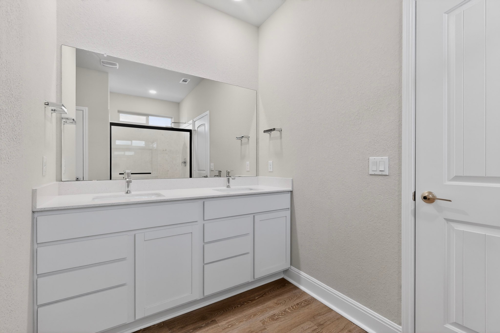 16809 Guido Cove Pflugerville, TX 78660 - Photo 19 of 40 Double vanity with white cabinetry, integrated sinks, chrome fixtures, and a large wall-mounted mirror