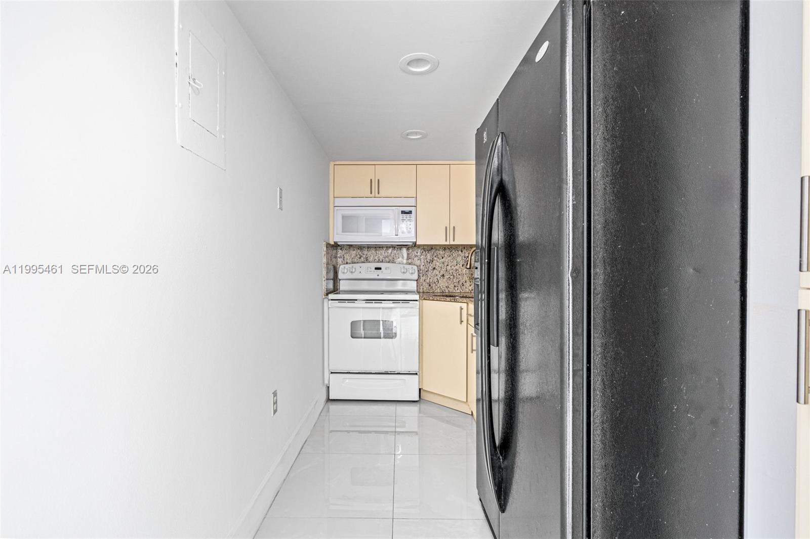 4801 Northwest 7th Street, Unit 40716 Miami, FL 33126 - Photo 7 of 26 a kitchen with white cabinets and white appliances
