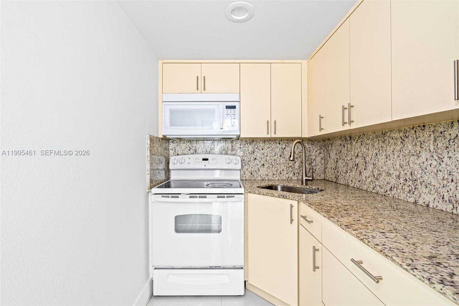 4801 Northwest 7th Street, Unit 40716 Miami, FL 33126 - Photo 8 of 26 a kitchen with a stove and white cabinets