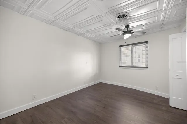 an empty room with wooden floor ceiling fan and windows