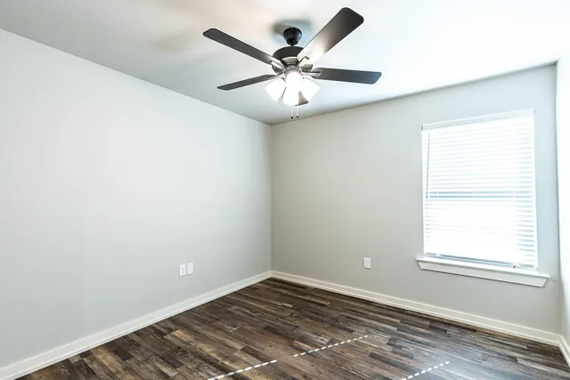 an empty room with a window and a fan
