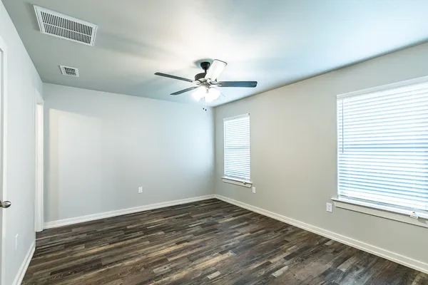an empty room with wooden floor and windows