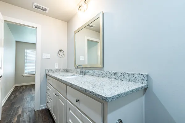 a bathroom with a granite countertop sink and a mirror