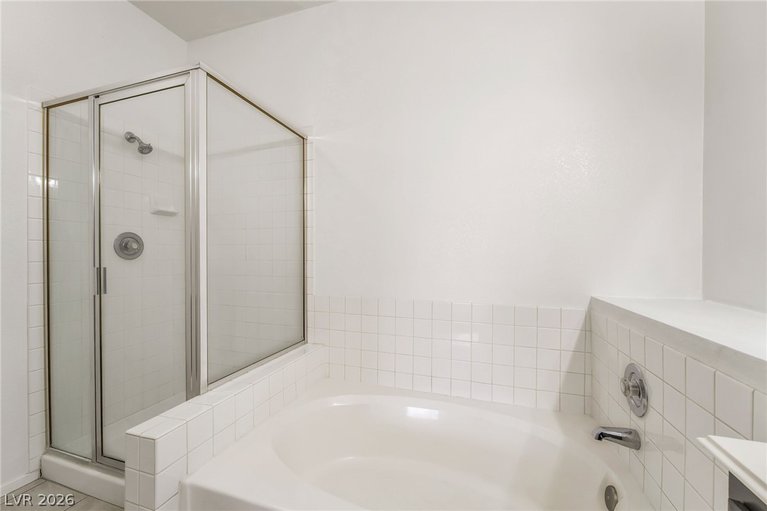 2201 Ramsgate Drive, Unit 811 Henderson, NV 89074 - Photo 22 of 36 A corner soaking tub and glass-enclosed shower create a serene bathing experience.
