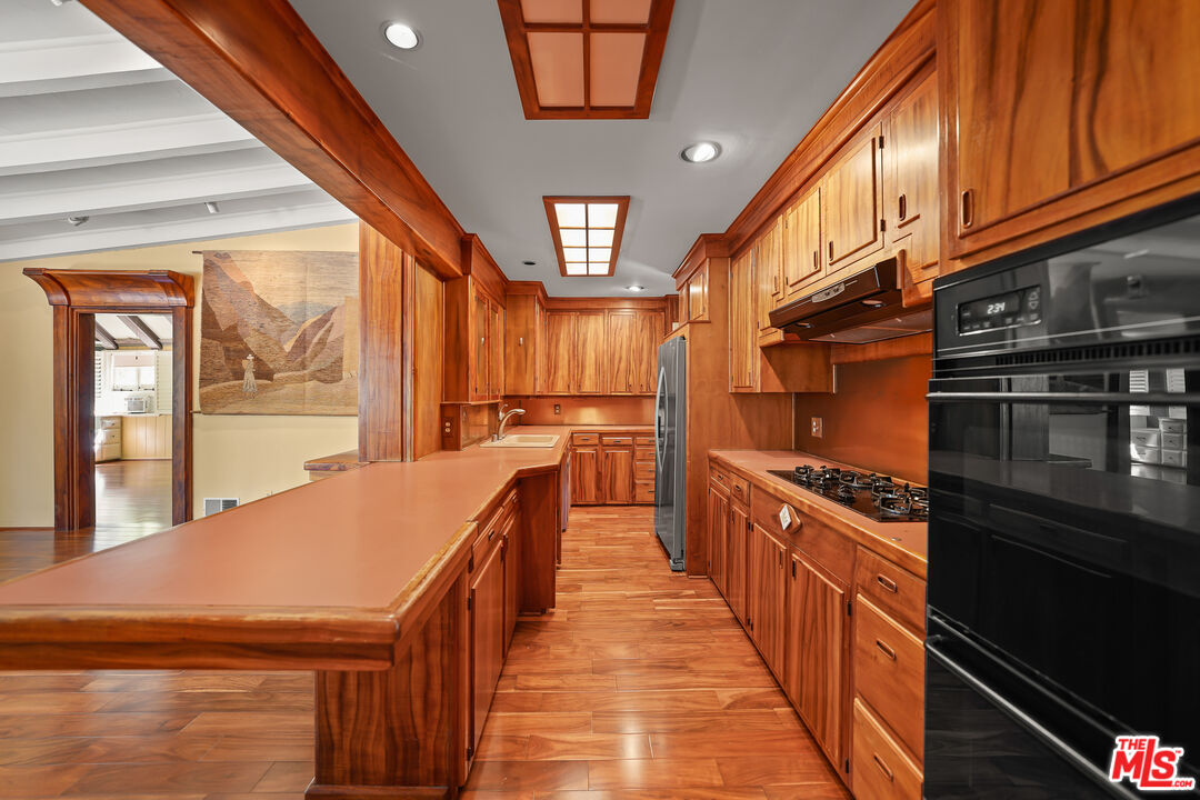 455 El Bosque Laguna Beach, CA 92651 - Photo 11 of 57 a kitchen with stainless steel appliances granite countertop a stove top oven a sink dishwasher and cabinets with wooden floor
