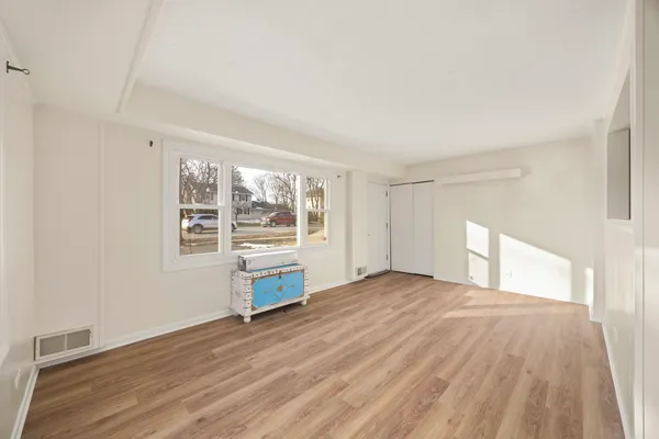 a view of an empty room with a window and wooden floor